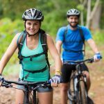 image of female and male riding bikes on a wooded trail