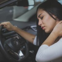 Woman grabbing her neck due to pain from whiplash injury after car accident