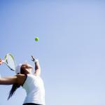 image of female serving tennis ball