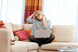 woman with laptop in her home having a neck pain