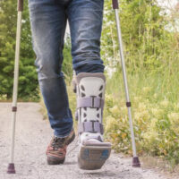 image partial weight bearing in a walking boot on the left and using crutches