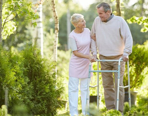 couple in nature with man using a walker