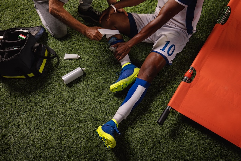 Soccer player injured knee during the game. Sport Doctors provide first aid to player on a professional football field.