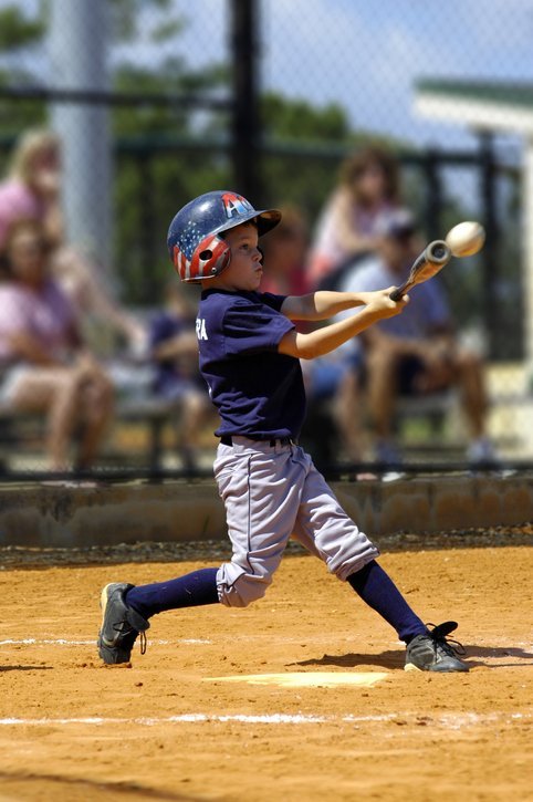 image of child swinging a baseball bat and hitting the ball
